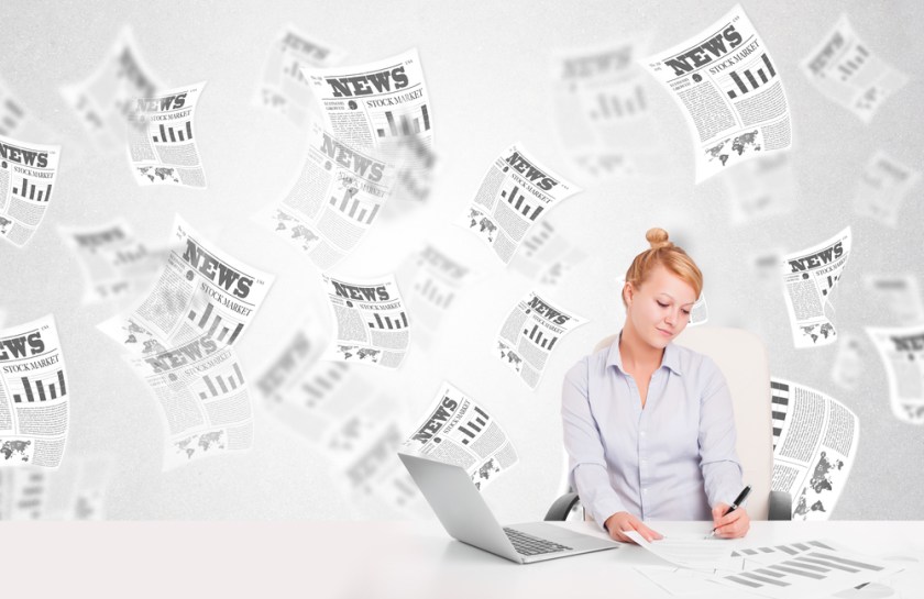Business-woman-at-desk-with-stock-market-newspapers-concept