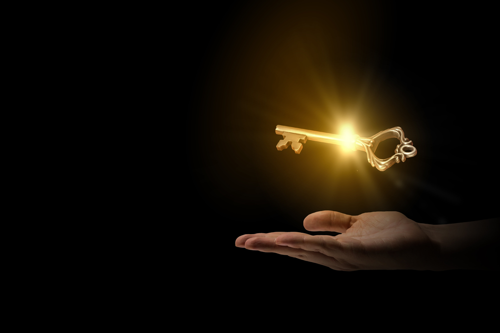 Close-up-of-human-hand-holding-golden-key