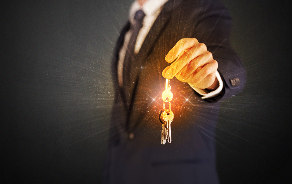 Formal-man-hand-over-shiny-keys-with-dark-background