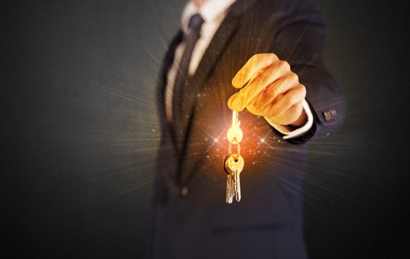 Formal-man-hand-over-shiny-keys-with-dark-background