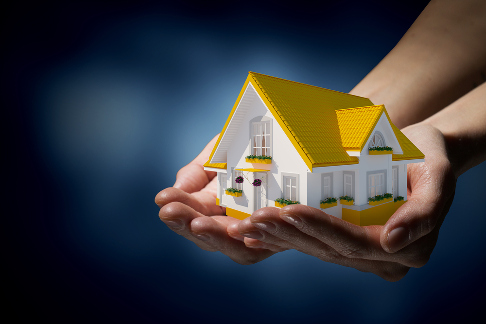 Human-hands-holding-model-of-dream-house