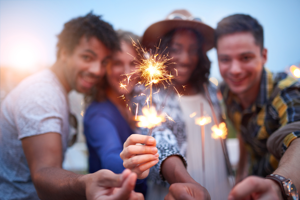 Multi-ethnic-millenial-group-of-friendsfolding-sparklers-on-rooftop-terrasse-at-sunset-1