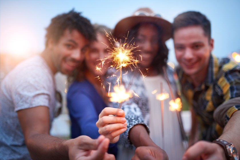 Multi-ethnic-millenial-group-of-friendsfolding-sparklers-on-rooftop-terrasse-at-sunset-1