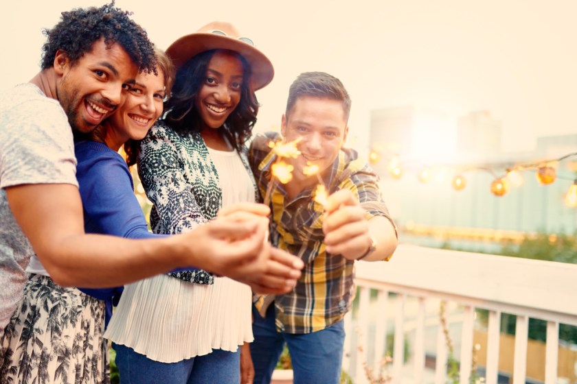 Multi-ethnic-millenial-group-of-friendsfolding-sparklers-on-rooftop-terrasse-at-sunset