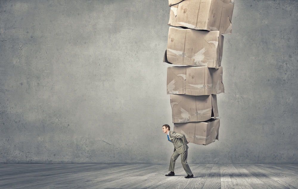 Young-businessman-in-suit-carrying-big-stack-of-carton-boxes