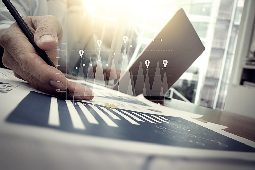 business-documents-on-office-table-with-smart-phone-and-digital-tablet-and-graph-financial-with-social-network-diagram-and-man-working-in-the-background