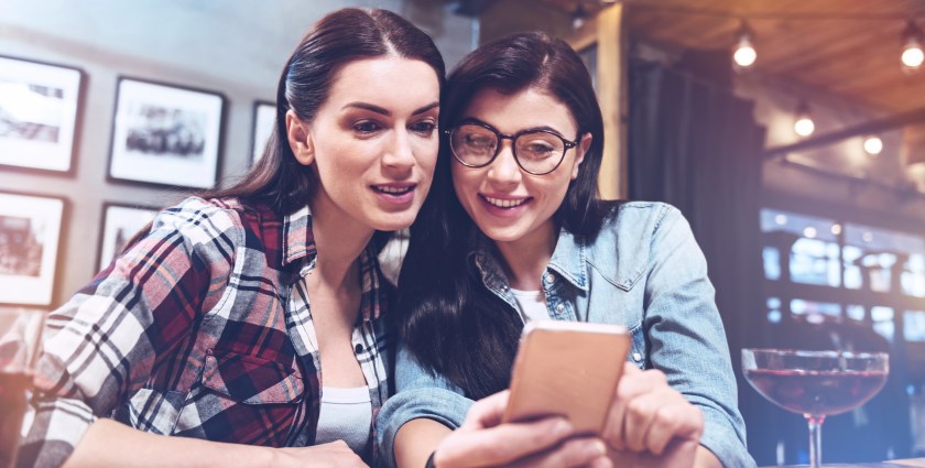 Positive beautiful women looking at the smartphone screen