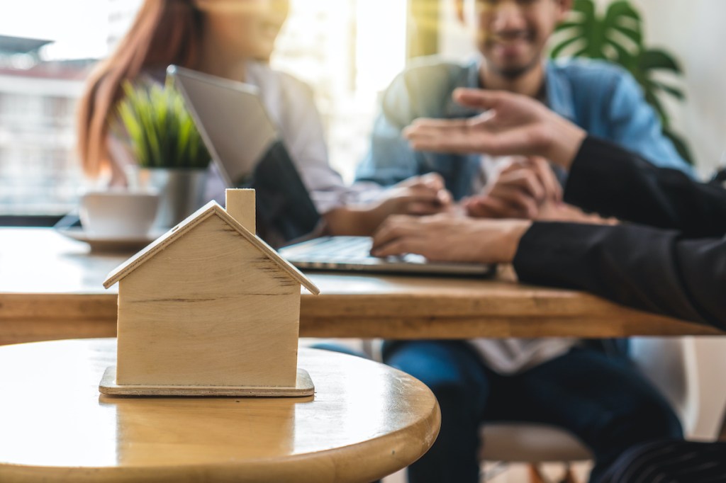 Closeup house model over the Sale representative offer the house price list and condition for house purchase or rental on the working space table in new house,Moving and House Hunting concept