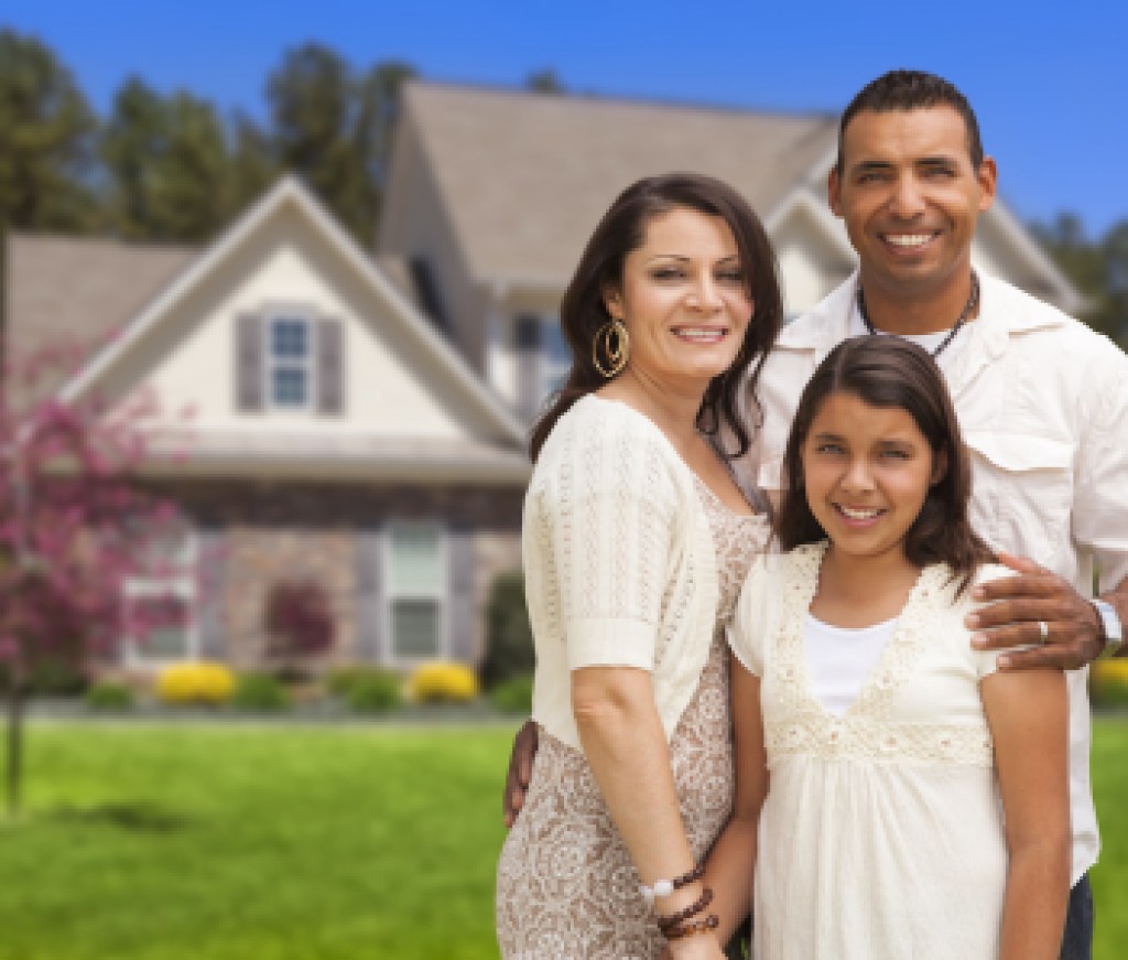 Happy Hispanic Mother, Father and Daughter in Front of Their Home.