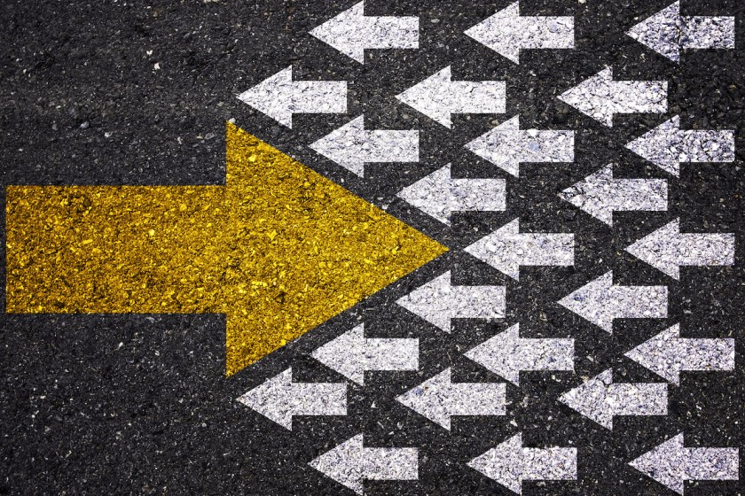 Different thinking and Business and technology disruption concept. Yellow big arrow opposite direction with white arrow on road asphalt.