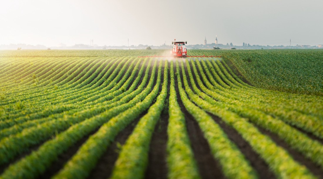 Tractor spraying pesticides at  soy bean field