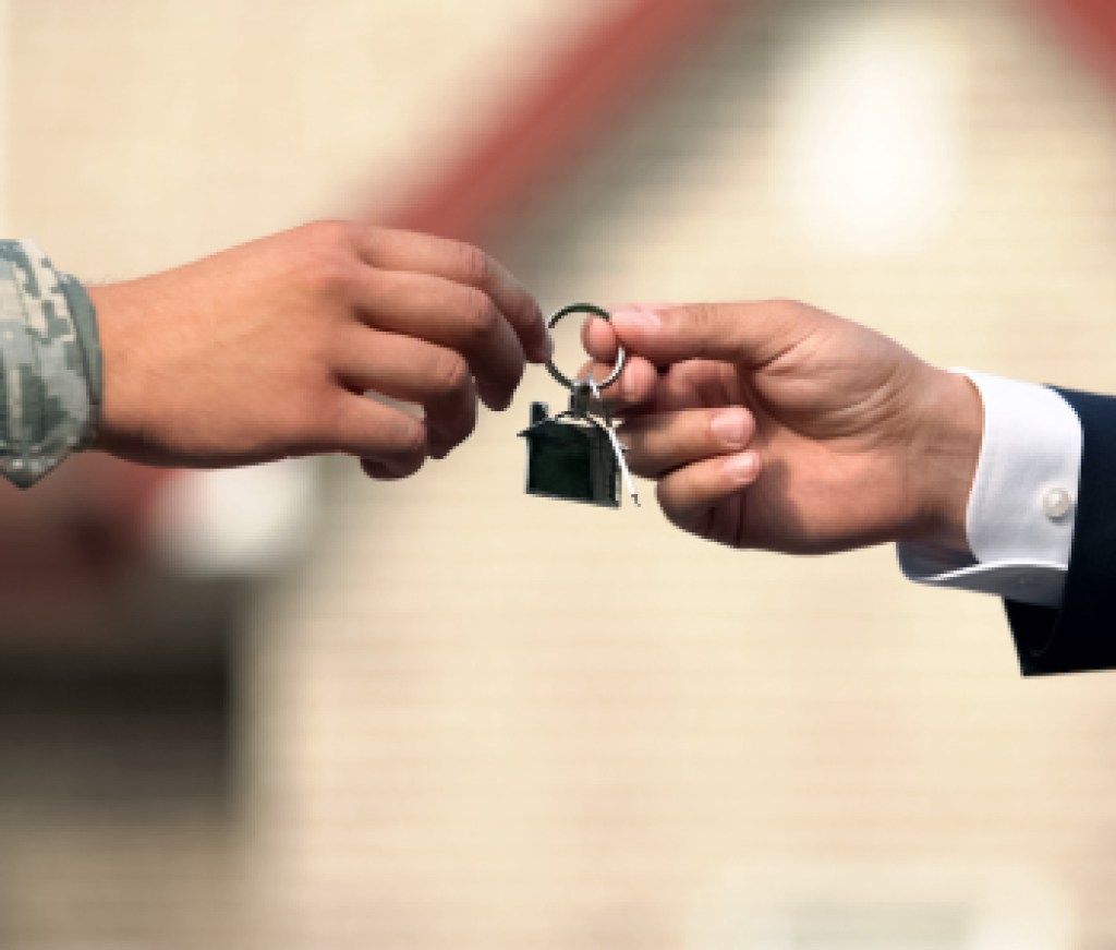 Man in business suit giving house key to man in military uniform, state support