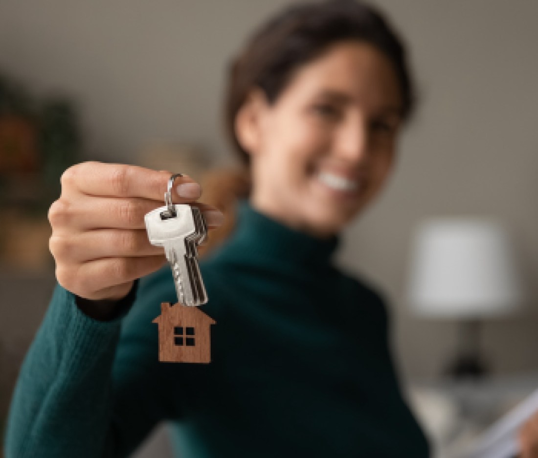 Close up focus on keys, smiling woman realtor selling apartment