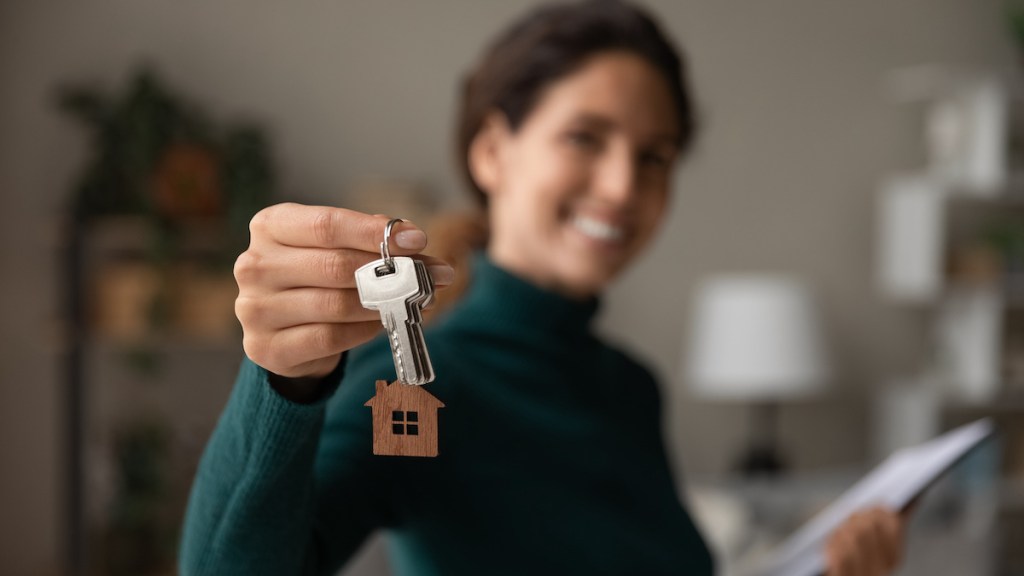 Close up focus on keys, smiling woman realtor selling apartment