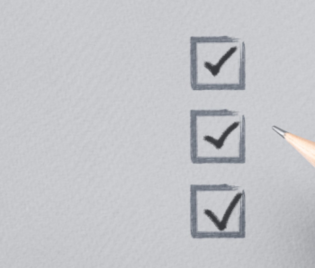 hand with pencil writing check mark on Checklist. Cropped Hand Marking On Check Box on Gray paper. Completed tasks are ticked off on a to-do list