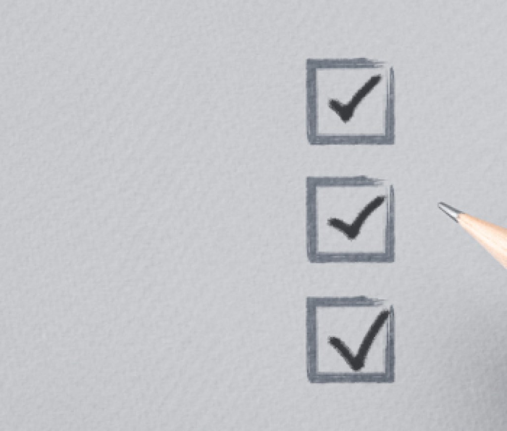 hand with pencil writing check mark on Checklist. Cropped Hand Marking On Check Box on Gray paper. Completed tasks are ticked off on a to-do list