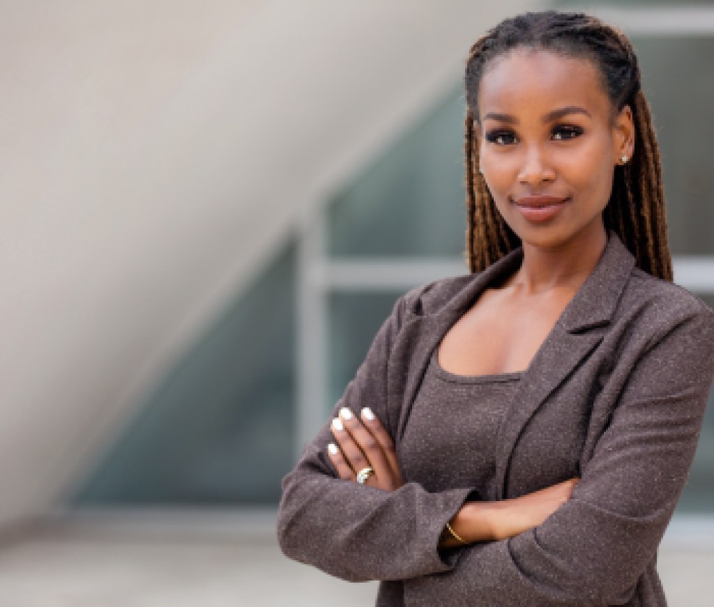 Beautiful female african american business woman CEO in a suit at the workplace, standing confidently with arms folded