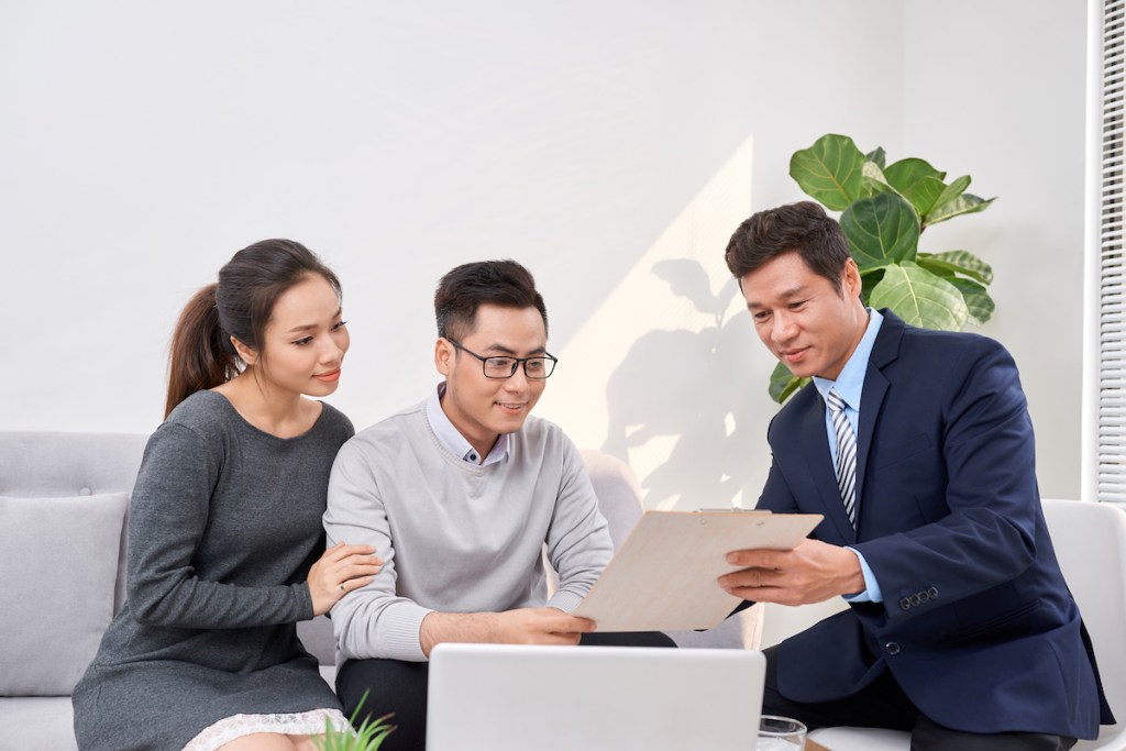 Sales Consultant showing new investment plans to young asian couple