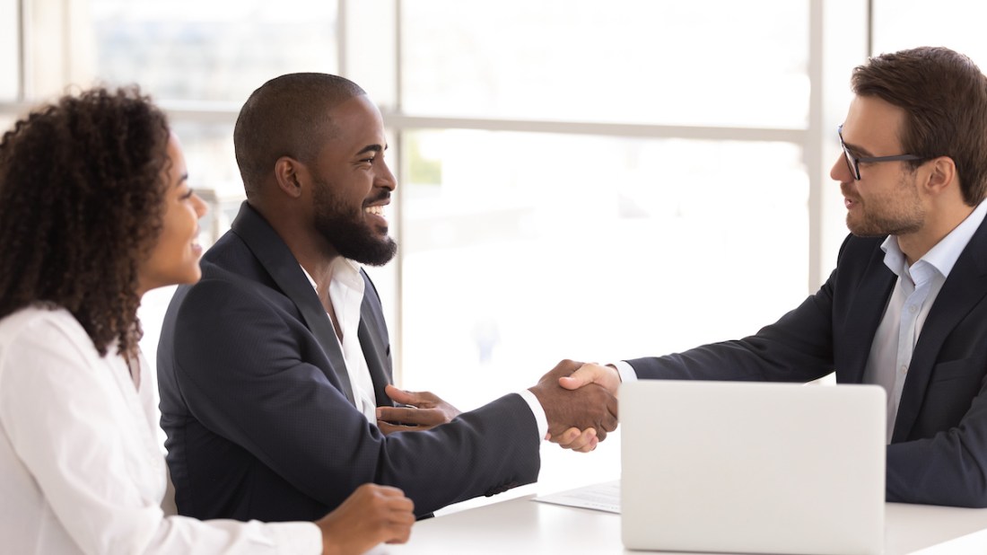 Happy sellers shake real estate agent's hand