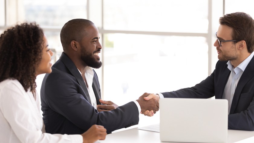 Happy sellers shake real estate agent's hand