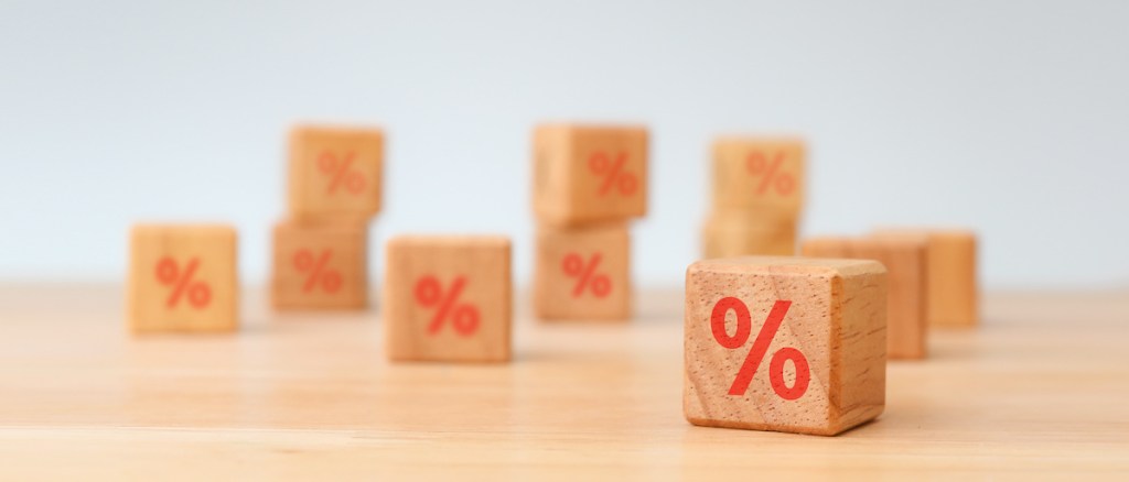 Interest rate financial and mortgage rates concept. Hand choosen wooden cube block with icon percentage symbol