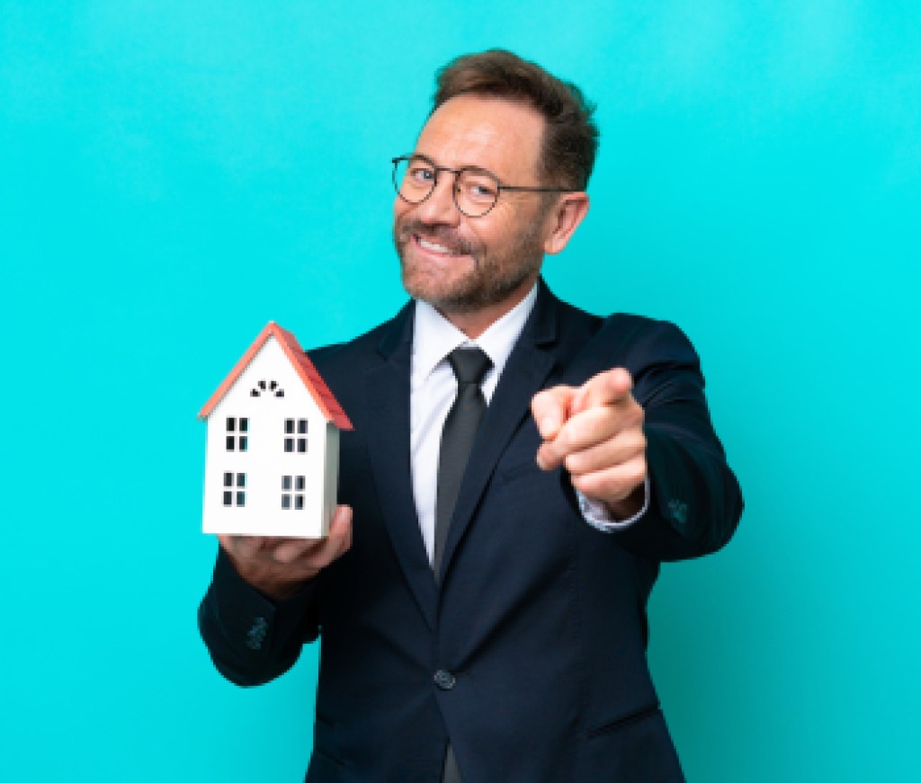 Real estate middle age agent man isolated on blue background pointing front with happy expression