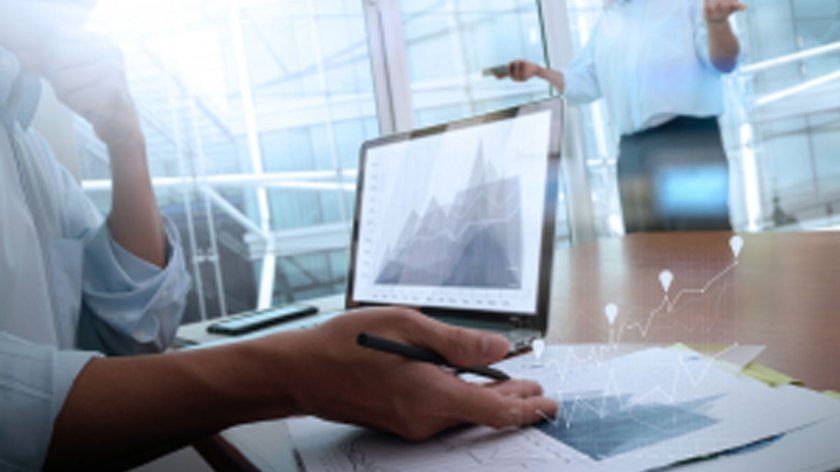 business-documents-on-office-table-with-smart-phone-and-laptop-computer-and-graph-business-with-social-network-diagram-and-two-colleagues-discussing-data-in-the-background