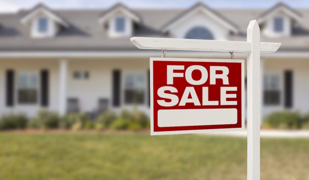 Red For Sale Real Estate Sign in Front of Beautiful New Home.